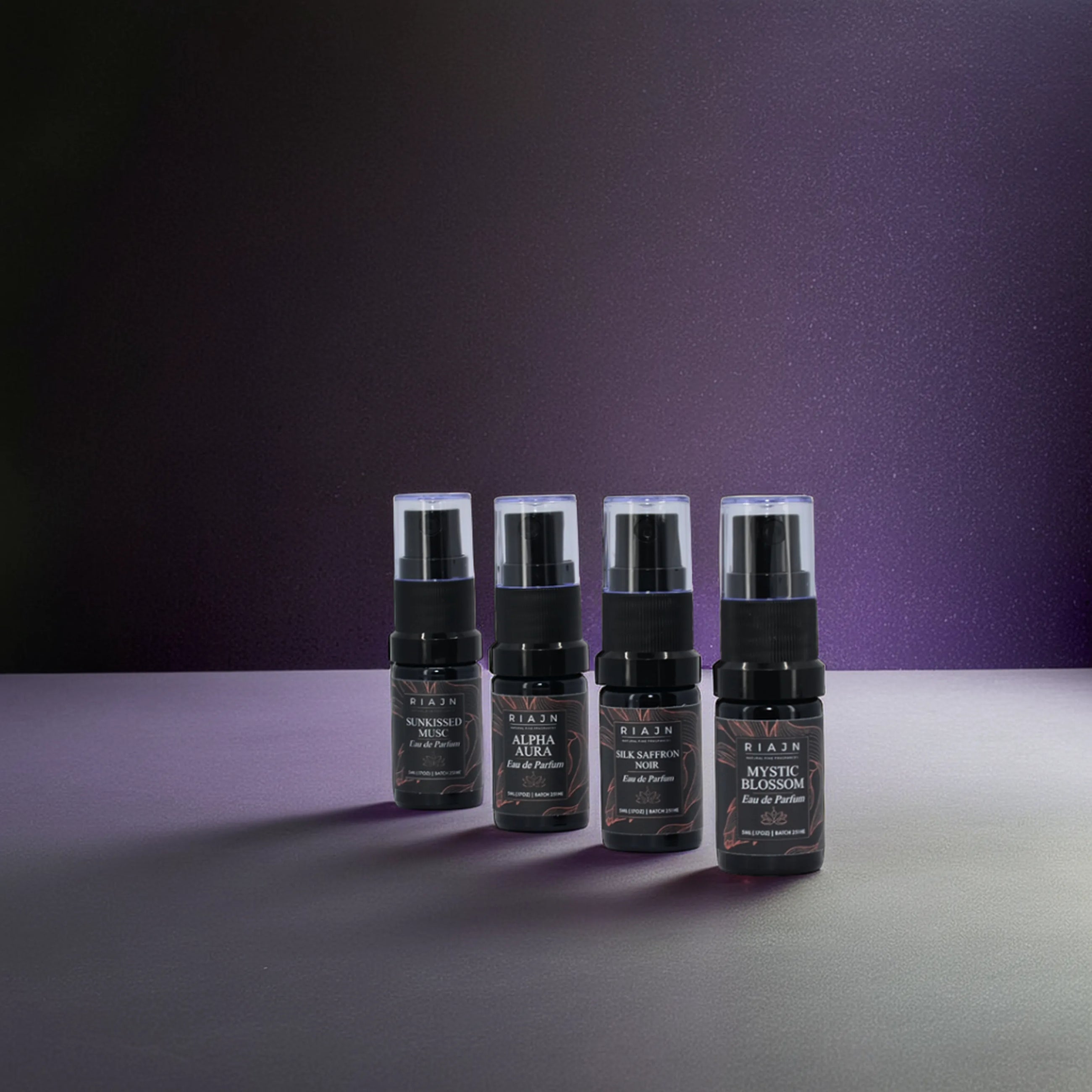 RIAJN Eau de Parfum Sample Set bottles standing on a grey floor with purple background with shadows. Top EDP sample sets. Top EDP fragrance sample set.