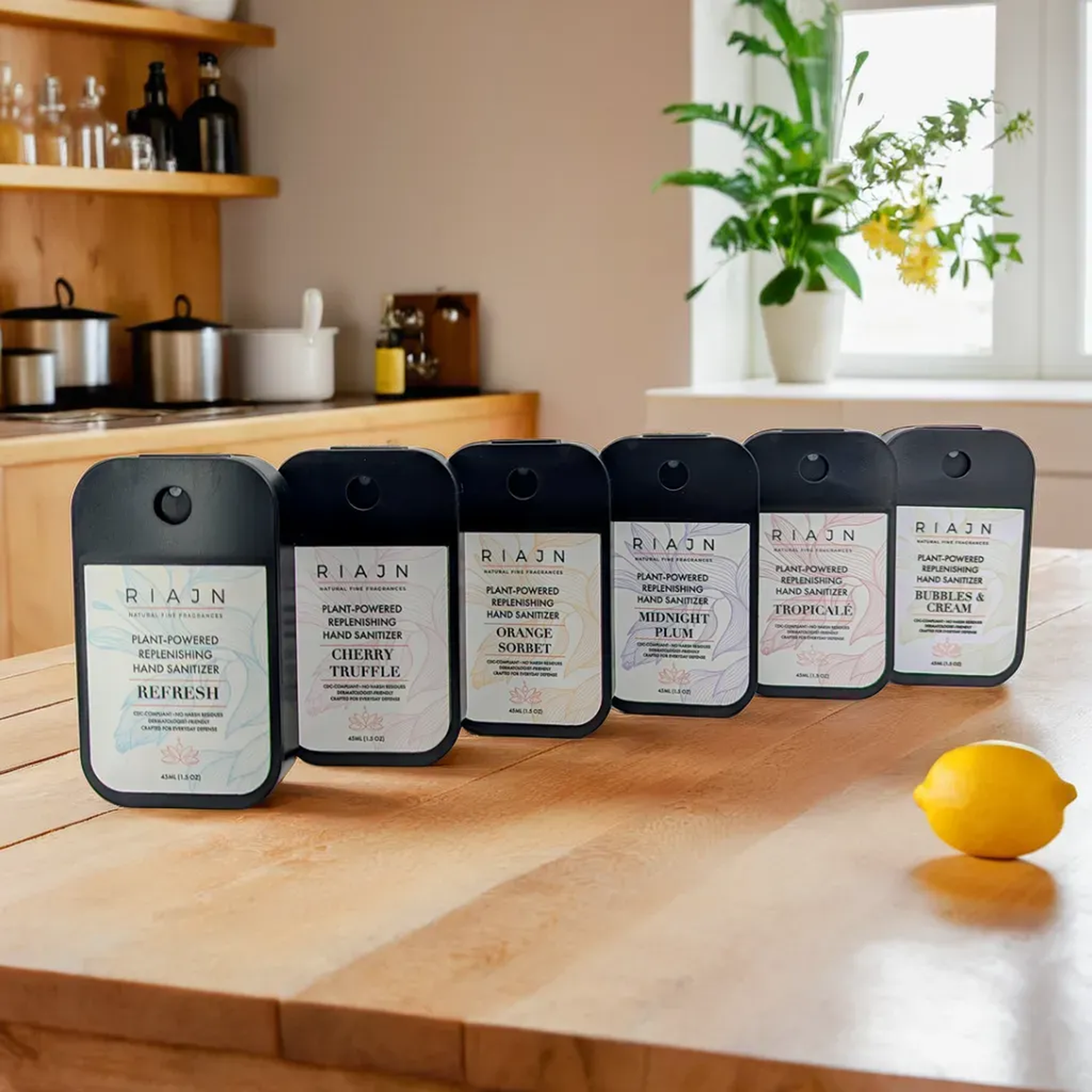 Row of RIAJN hand soap bottles on a kitchen counter with a lemon and plants in the background.