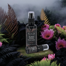 Riajan Alpha Aura perfume bottle surrounded by pink flowers and black ferns