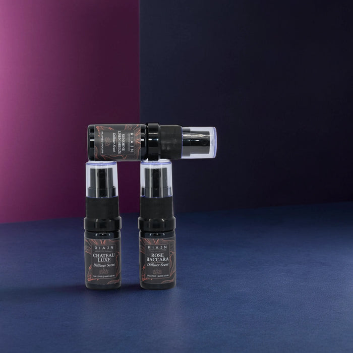 RIAJN Diffuser Scent Sample Set bottles standing on a royal blue floor near a bi-color purple and navy blue wall . Premium diffuser fragrance oils.