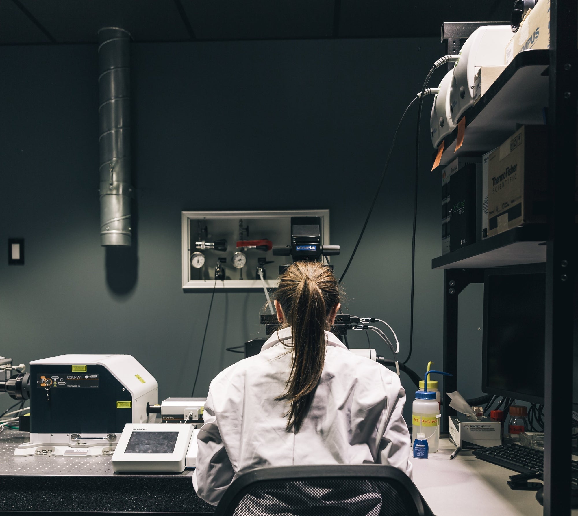 A laboratory worker sitting behind a desk running tests using equipment. RIAJN clean, vegan, and non-toxic gender-neutral fragrances.