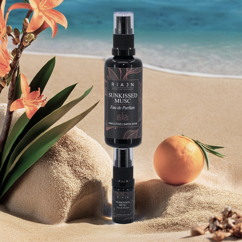 Riaan Sunkissed Musc eau de parfum bottle on a beach with orange flowers and an orange.