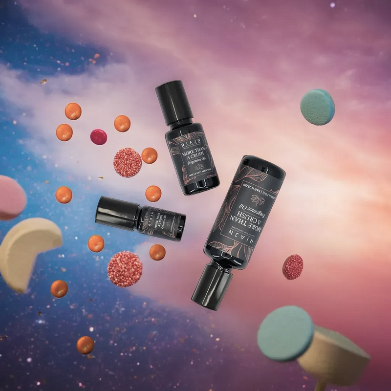 Three RIAJN More Than a Crush fragrance oil bottles with floating colorful candies against a space-themed setting.