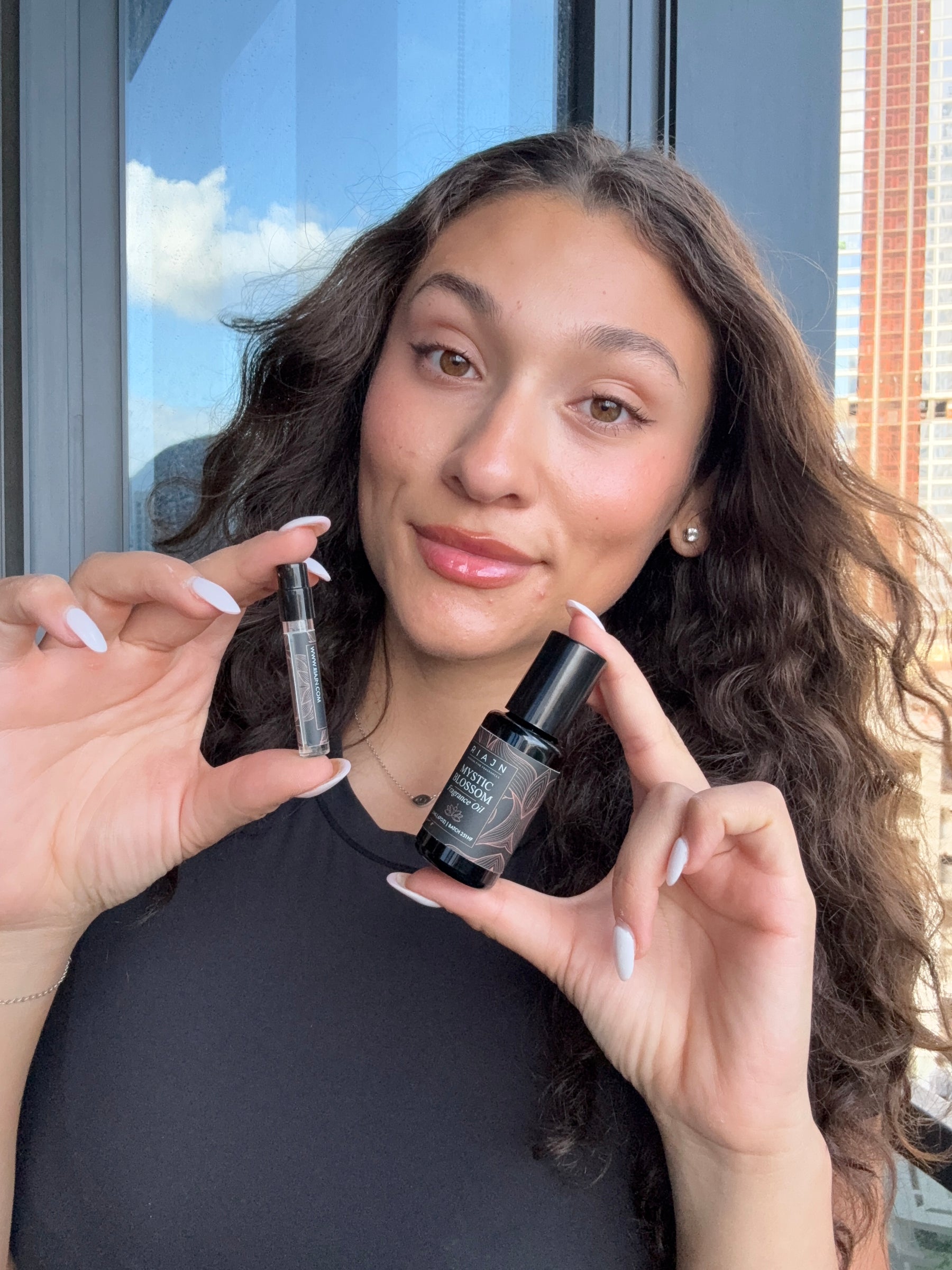 Woman holding two bottles of mystic blossom fragrances with a blurred background