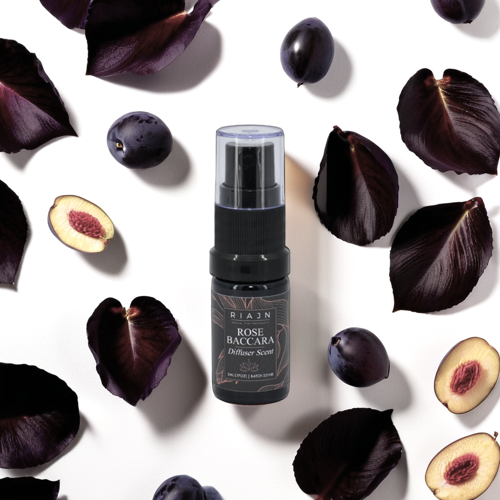 RIAJN Rose Baccara diffuser spray surrounded by dark purple leaves and figs on a white background