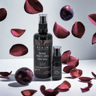 Rian Rose Baccara room spray with plum and rose petals and plums falling from the sky on a light background