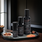 Riajn Silk Saffron Noir fragrance oil bottles on a tray with almonds and saffron.