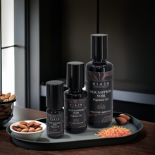 Riajn Silk Saffron Noir fragrance oil bottles on a tray with almonds and saffron.
