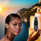 RIAJN Sunshine Linen Breeze Diffuser Scent bottle held by an African American female model in front of the Amalfi coast. Top linen fresh room deodorizer.
