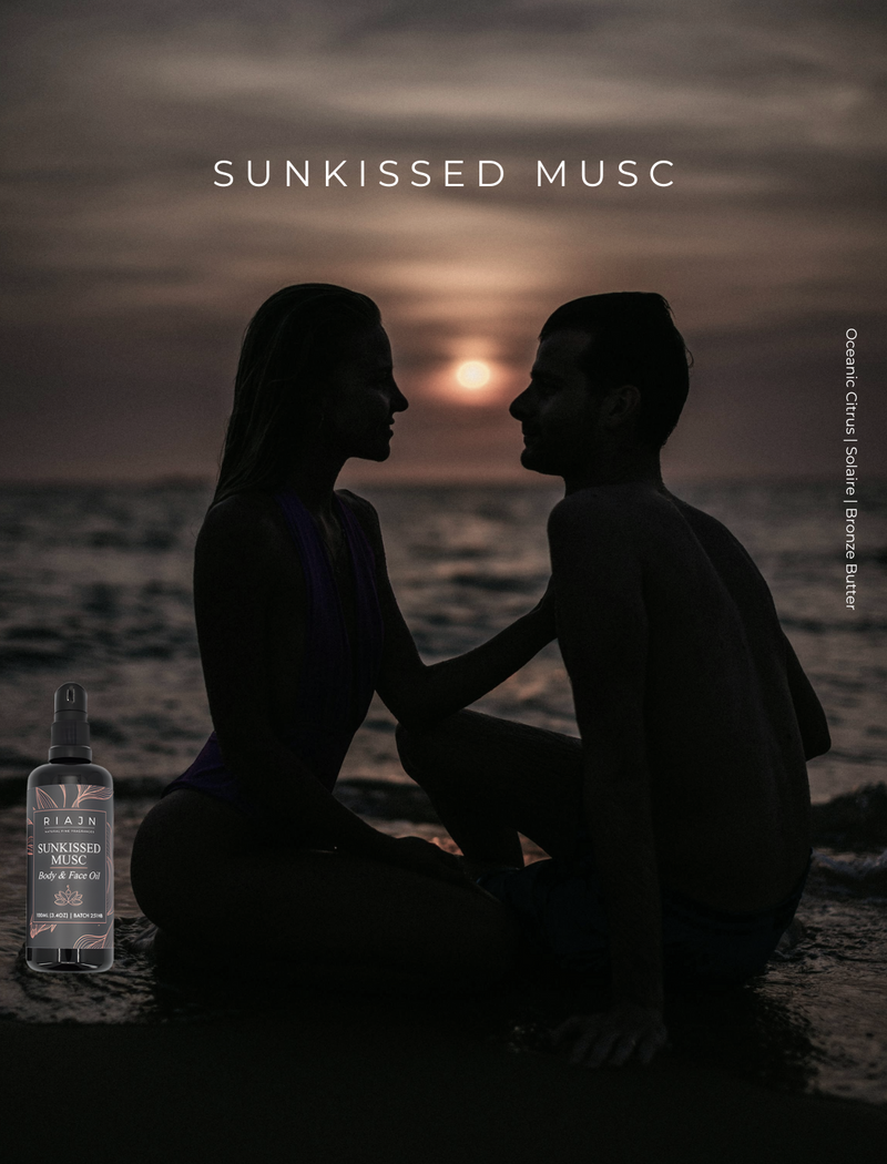 Silhouette of a couple sitting on a beach with a sunset, featuring a bottle labeled 'Sunkissed Musc'.